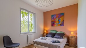 A bedroom with a bed, a chair, a window, and a painting on the wall. - Renovated house with garden near Angers (Rochefort-sur-Loire)