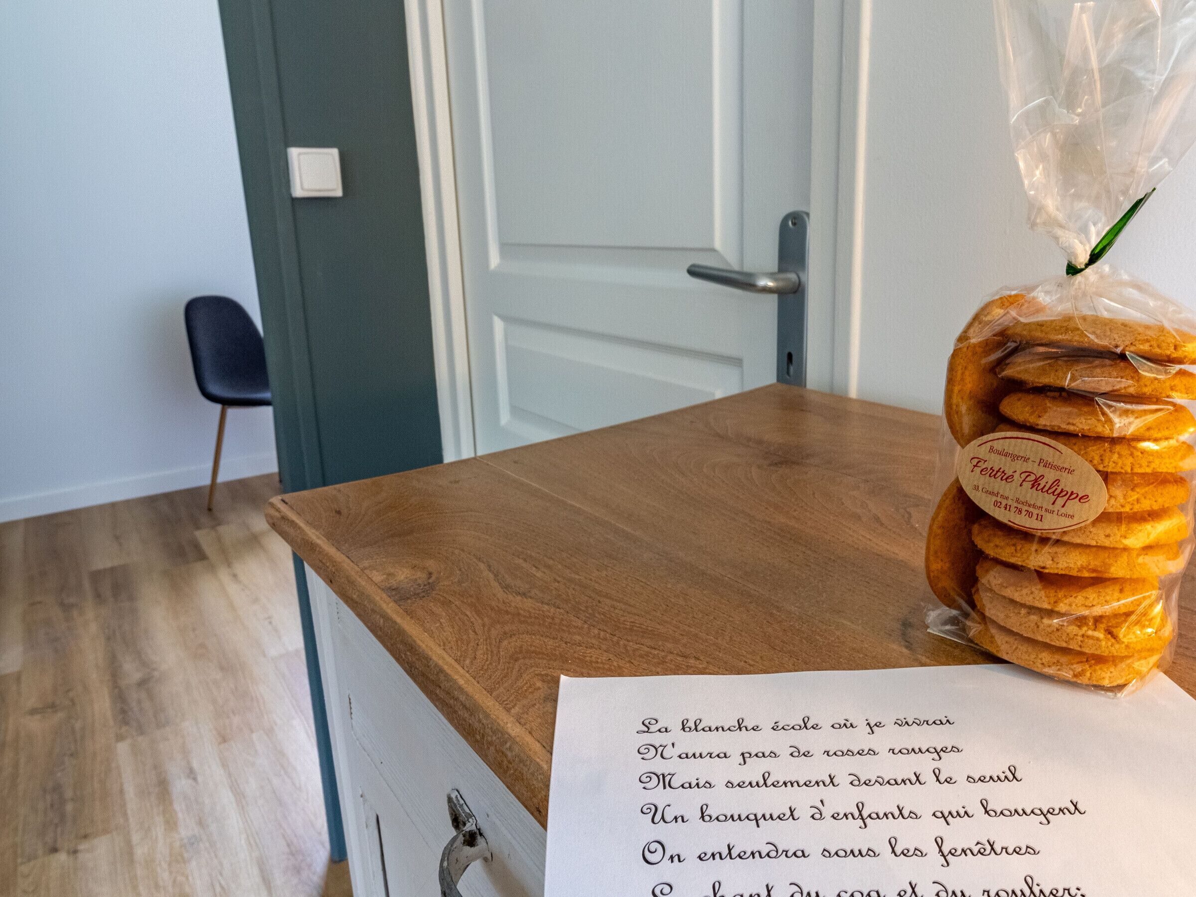 A wooden table with a plastic bag of bread and a paper with French text.