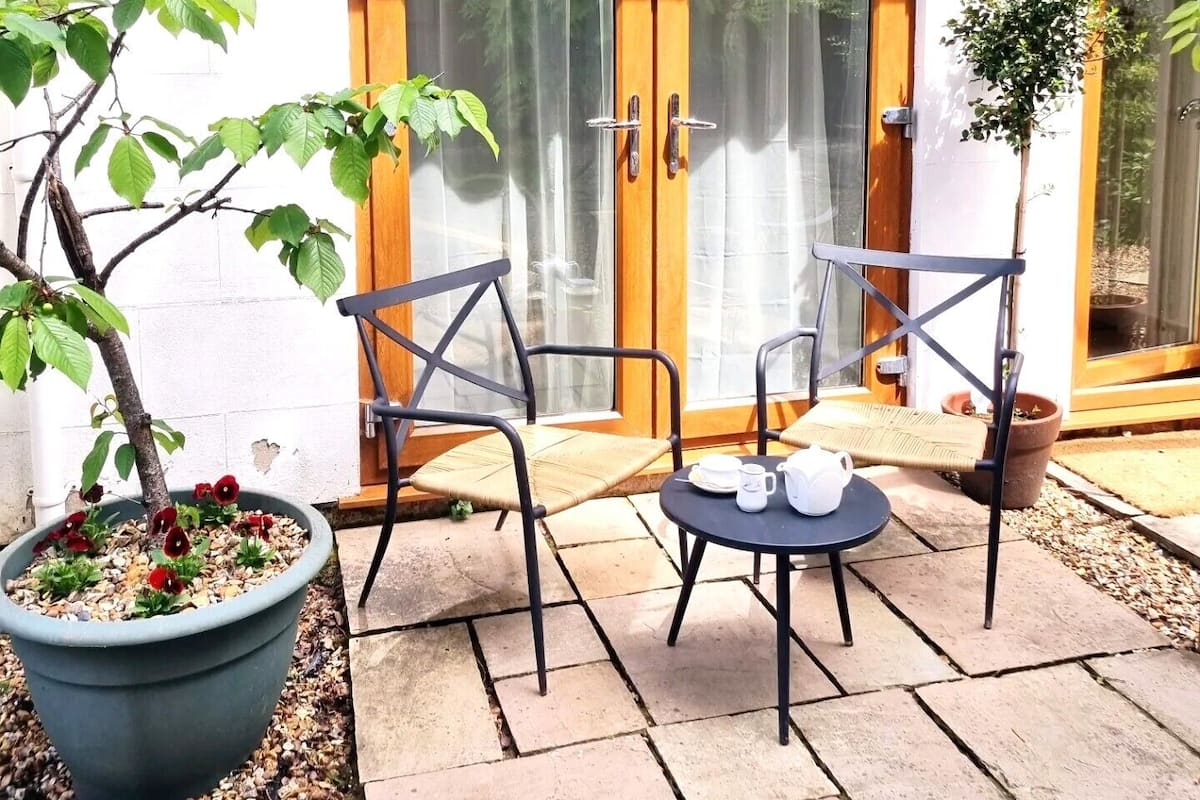 A patio with two chairs, a table, and a potted plant.