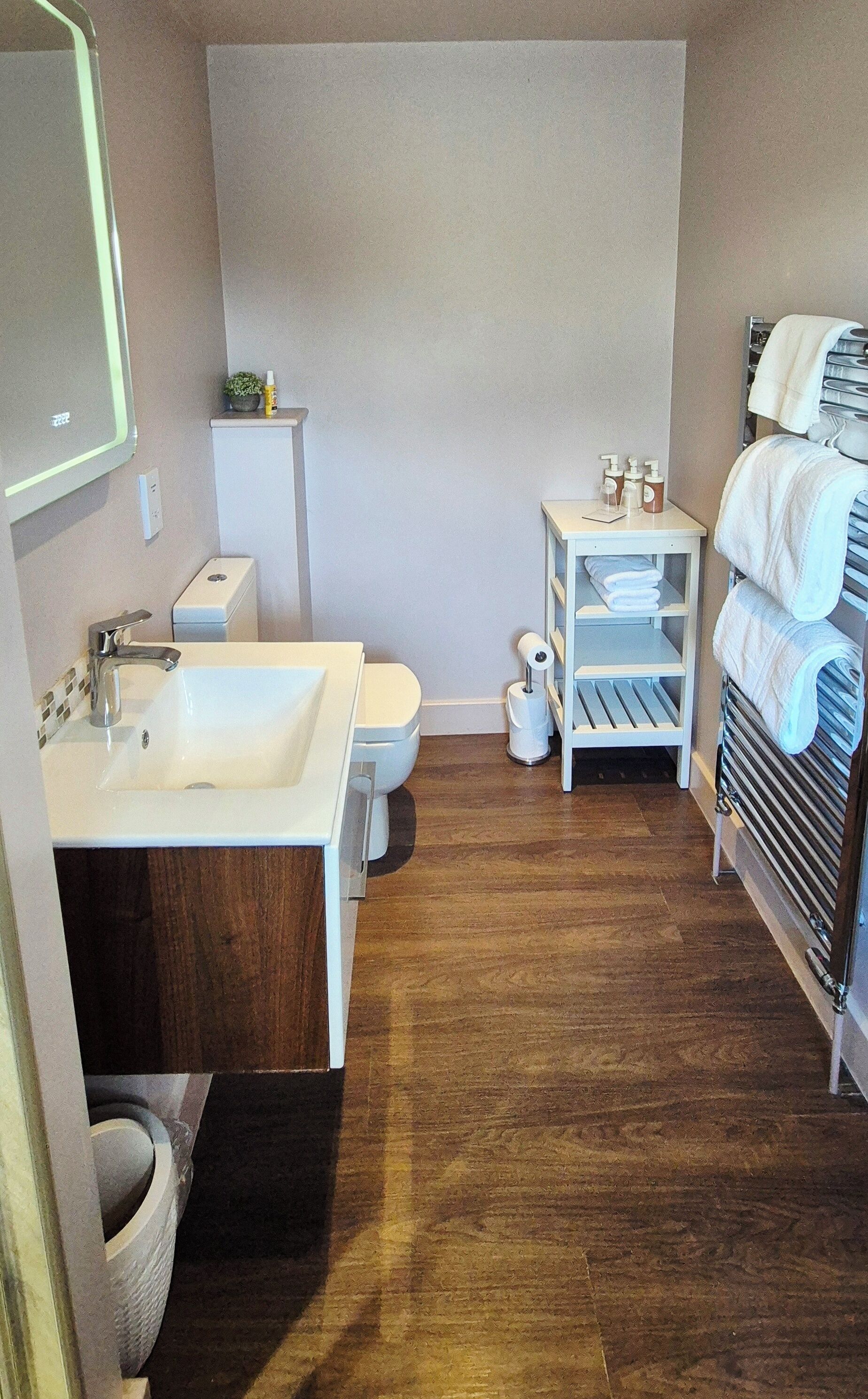 Un baño con lavamanos, inodoro y perchero para toallas.