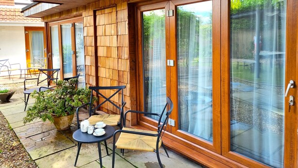 Ein überdachter Patio-Bereich mit Holzwänden und großen Glasschiebetüren.