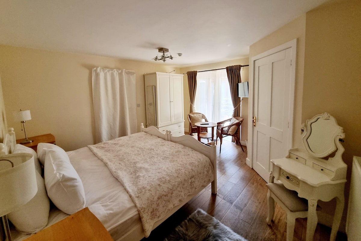 A hotel room with a bed, a desk, a chair, a wardrobe, and a television.