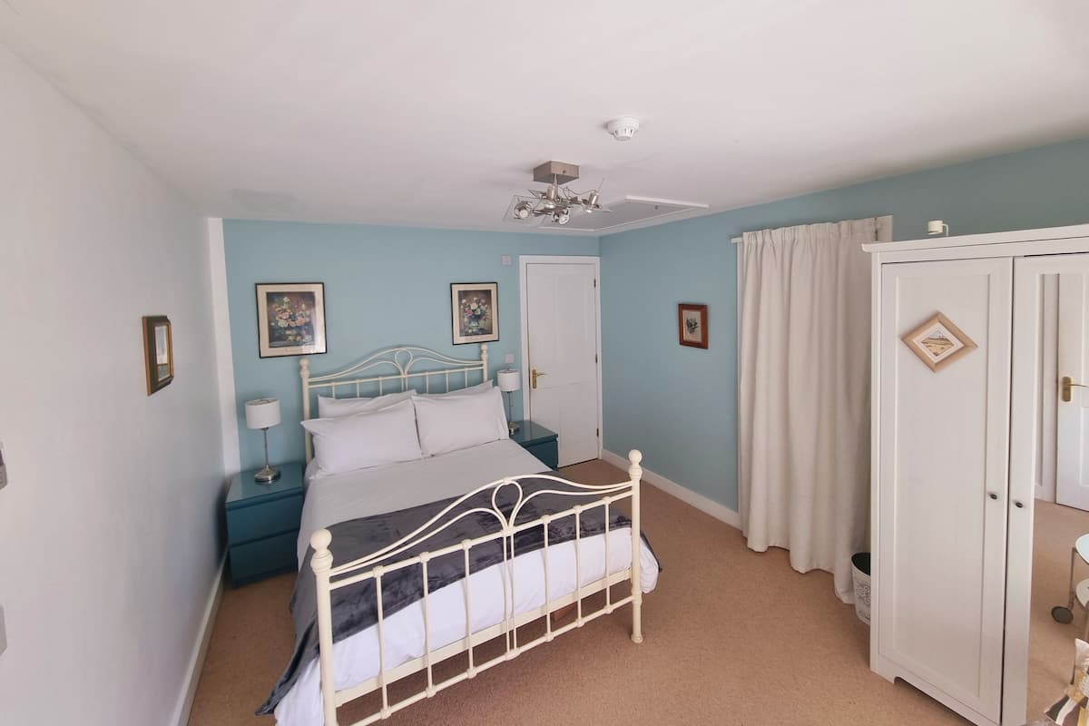 A bedroom with a bed, nightstands, a wardrobe, and a ceiling fan.