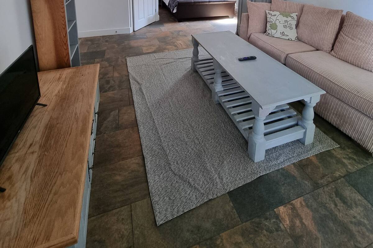 A modern living room with a wooden TV stand, a grey sofa, and a patterned rug.