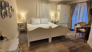 Ein Schlafzimmer mit Bett, Nachttischen, einem Kleiderschrank, einem Sessel und einem Spiegel.