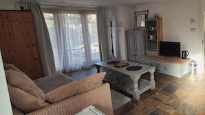 Ein Wohnzimmer mit einer Couch, einem Tisch, einem Fernseher und einem Schrank.