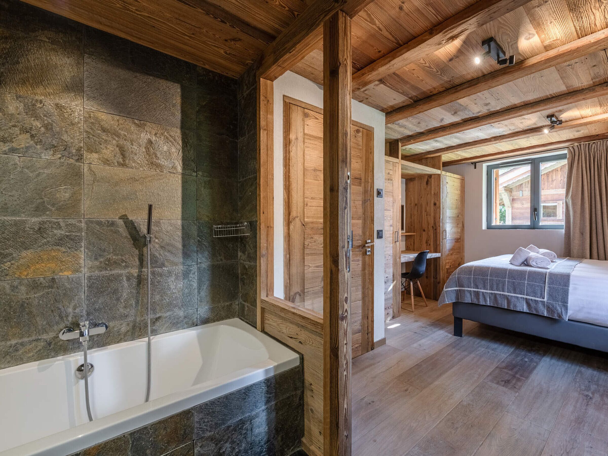 A bathroom with a bathtub, shower, and stone walls.