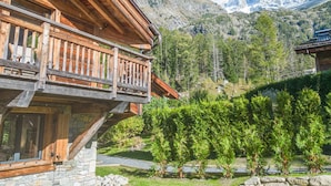 A wooden chalet with a balcony overlooking a mountainous landscape.