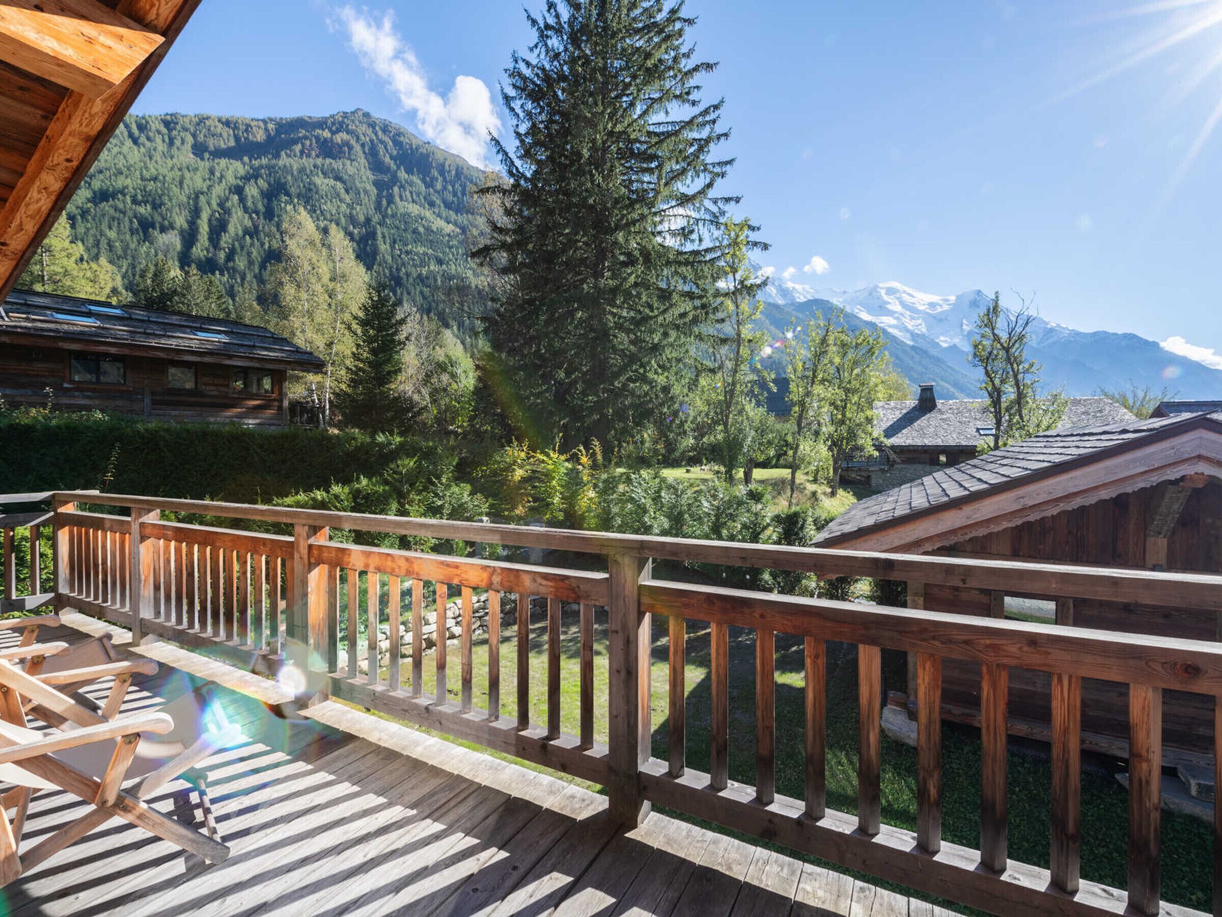 A wooden deck with a view of a mountain range and a pool.