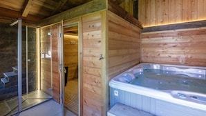 A wooden cabin with a hot tub, a shower area, and a door leading to a bathroom.