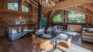 A wooden interior with a dining table set for four, a sofa, and a fireplace.