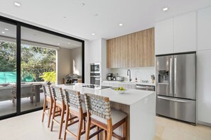 A modern kitchen with a large island, stainless steel appliances, and a view of the outdoors.