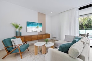 Una sala de estar moderna con un sofá, sillones, una mesa de centro y un televisor montado en la pared.