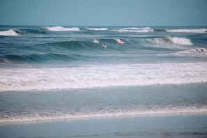 A beach with waves and surfers.