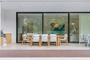 Un comedor moderno con separador de vidrio, mobiliario de madera y una lámpara colgante.