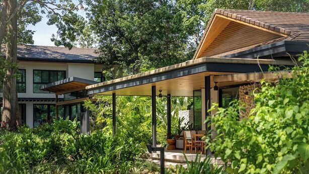 A modern house with a covered outdoor area, surrounded by lush greenery. - Seasons at Ceiba (Hacienda Pinilla)