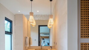 A modern bathroom with a large mirror, wooden vanity, and pendant lights. - Seasons at Ceiba (Hacienda Pinilla)