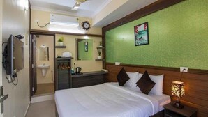 A hotel room with a bed, bedside lamp, and a green textured wall. - Gems9 Airport Hotel (Nedumbassery)