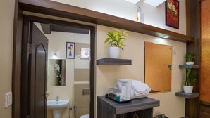 A hotel bathroom with a sink, mirror, towel rack, and a small table with toiletries. - Gems9 Airport Hotel (Nedumbassery)