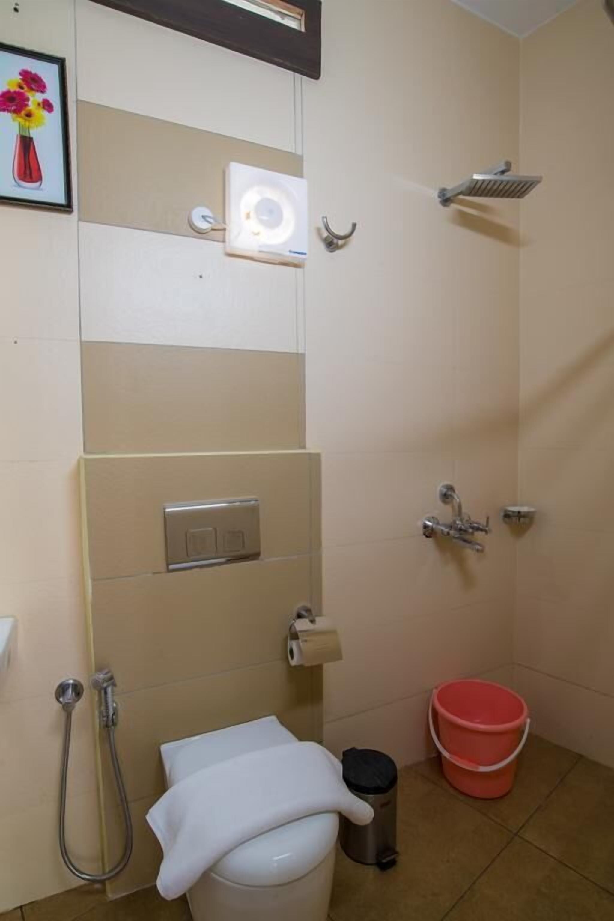 A small bathroom with a toilet, a shower, a sink, and a trash bin.