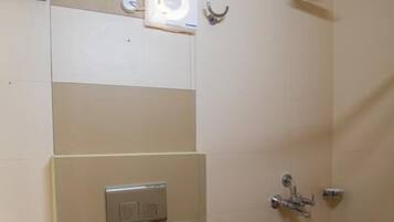 A small bathroom with a toilet, a shower, a sink, and a trash bin.