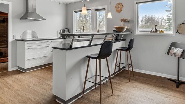 Une cuisine moderne dotée d’un îlot central, de tabourets de bar et de grandes fenêtres.