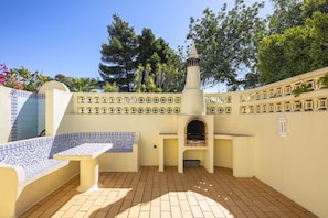 A patio with a built-in grill, a seating area, and a decorative wall with a lantern. - Casa San Michel - holiday villa with private pool, air-conditioning and sea view (Lagoa)