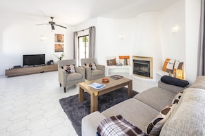 A modern living room with a sofa, armchairs, a coffee table, a fireplace, and a television. - Casa San Michel - holiday villa with private pool, air-conditioning and sea view (Lagoa)