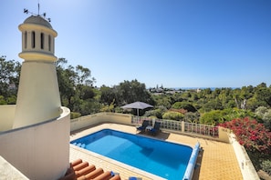 A swimming pool with a view of the sea, surrounded by greenery and a white tower. - Casa San Michel - holiday villa with private pool, air-conditioning and sea view (Lagoa)