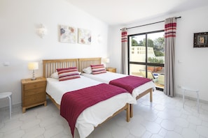 A bedroom with two beds, a wooden headboard, and a view of the outdoors through a large window.