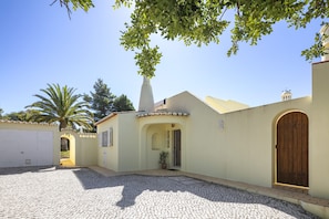 A house with a paved driveway, a wooden door, and a small garden area. - Casa San Michel - holiday villa with private pool, air-conditioning and sea view (Lagoa)