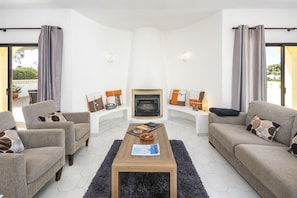 A living room with a fireplace, two sofas, a coffee table, and a view of the outdoors.
