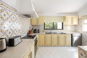 A kitchen with hexagonal patterned tiles, a stainless steel toaster, a coffee maker, and a dishwasher.