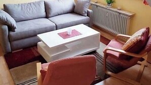A living room with a grey sofa, a white coffee table, and a wooden chair.
