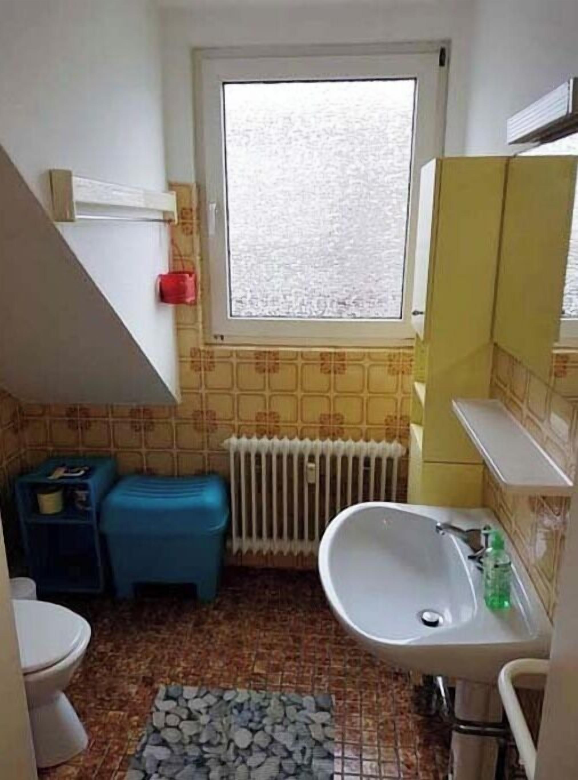 Ein kleines Badezimmer mit Toilette, Waschbecken und Fenster.