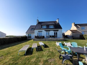 Ein Haus mit Balkon, Sitzbereich im Freien mit Stühlen und Tischen sowie einem gepflegten Rasen.