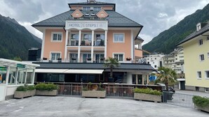 Hotel chiamato "HOTEL 24 STEPS" con un balcone e una insegna che indica un ristorante al piano terra.