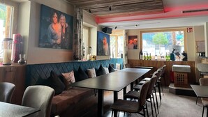 Un ristorante con travi in legno a soffitto, una panca imbottita blu e un'area bar con bottiglie e una cassa.