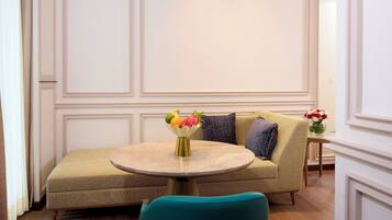 A room with a round table, a sofa, and a teal chair.