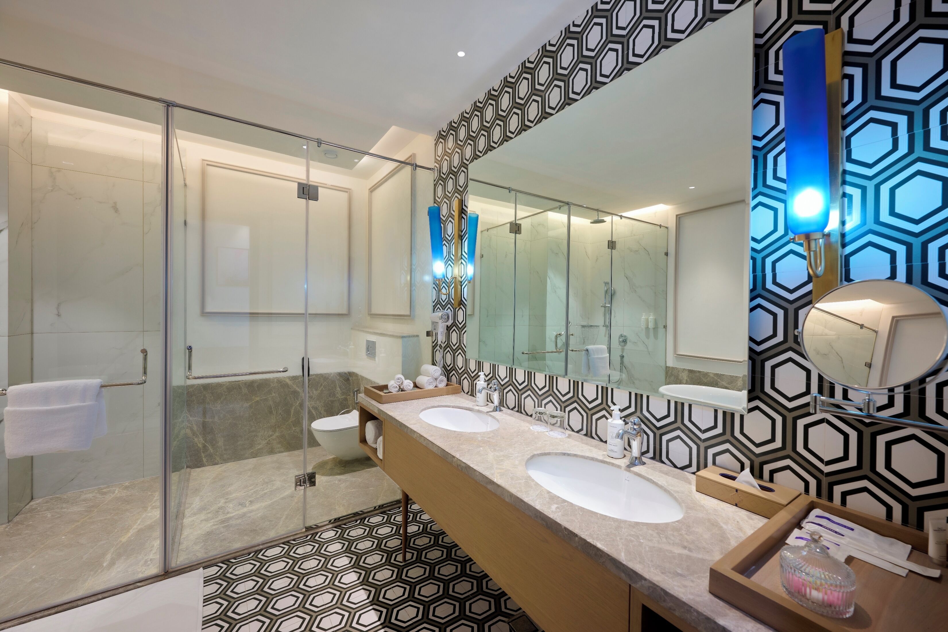 A modern bathroom with a glass shower enclosure, two sinks, and a large mirror.
