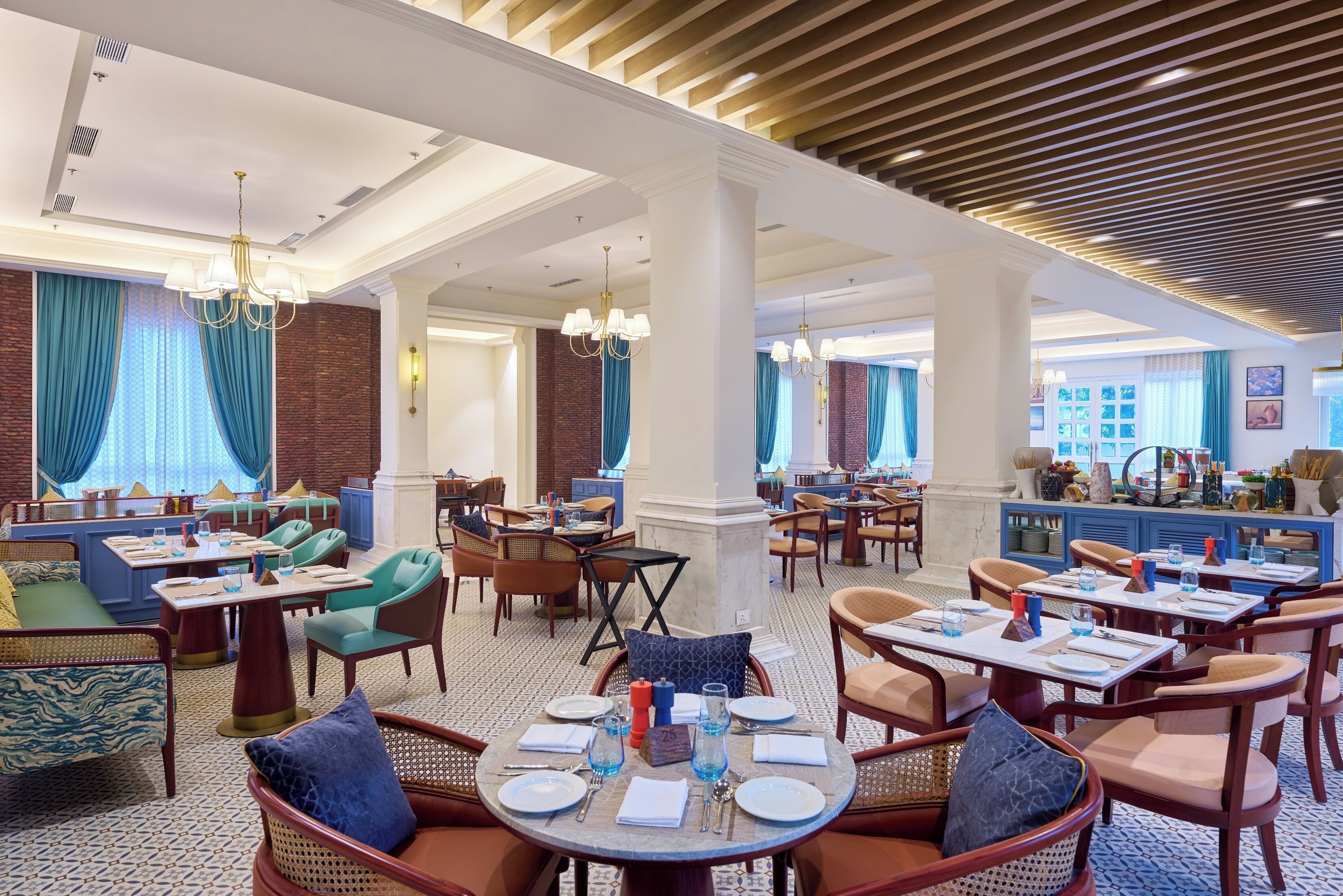 Un restaurante espacioso con techos altos, candelabros y una variedad de disposiciones de asientos, incluyendo mesas y cabinas.