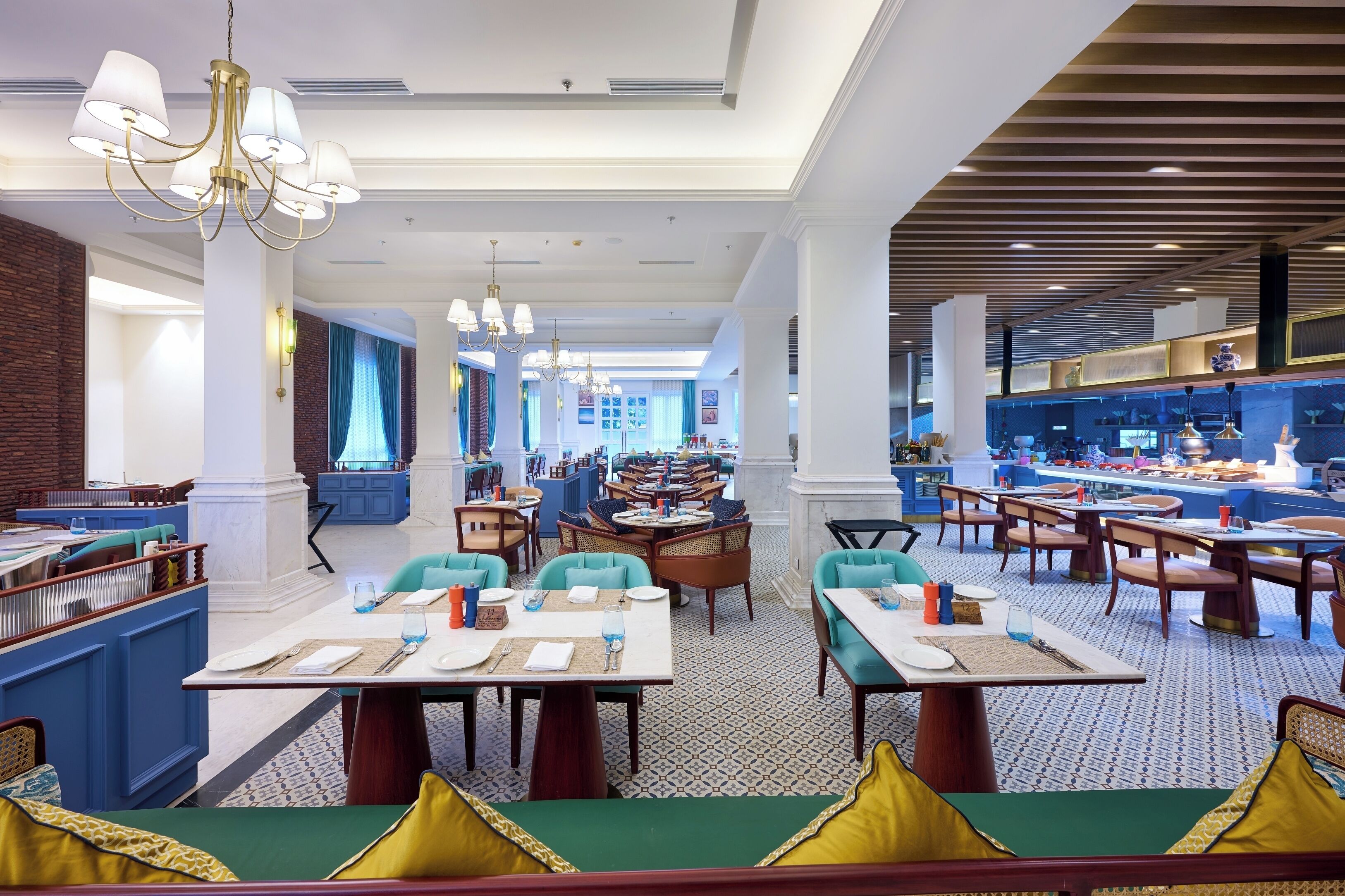 A spacious restaurant with high ceilings, multiple dining areas, and a modern chandelier.