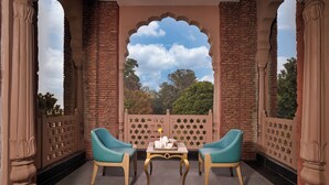 A balcony with two turquoise chairs, a table with a tea set, and a view of trees through a star-patterned fence. - Sarovar Premiere Amritsar (Amritsar)