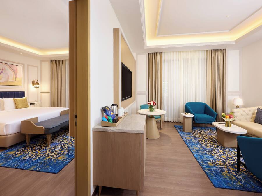 A hotel room with a bed, a desk, a sofa, and a chair.
