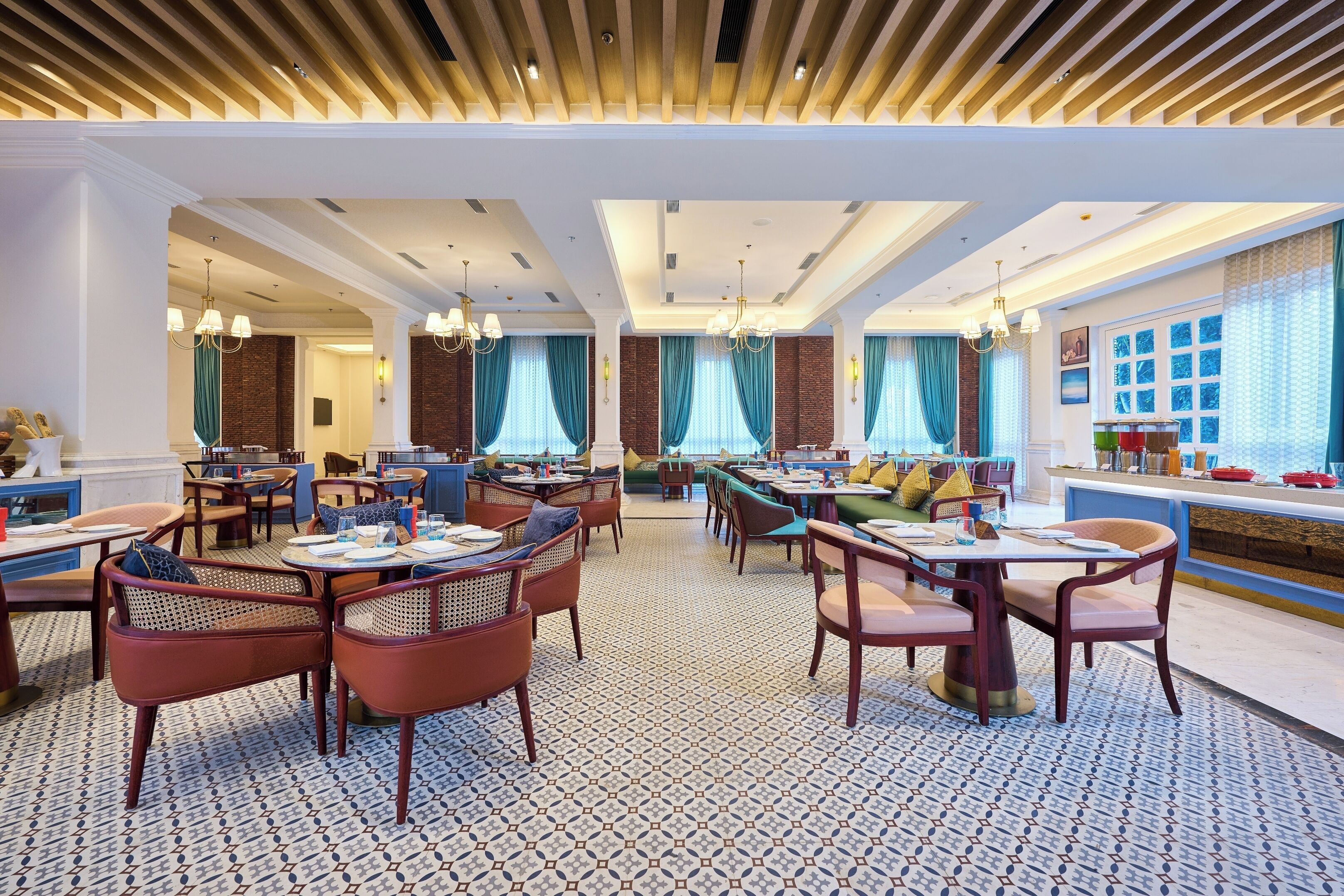 A spacious restaurant with high ceilings, patterned flooring, and multiple dining areas with chairs and tables.