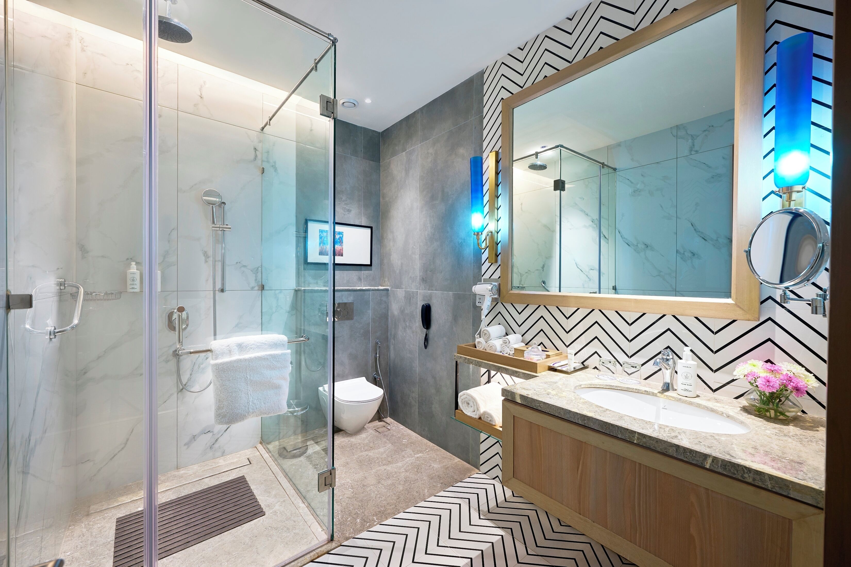 Une salle de bain moderne avec une douche à parois de verre, des toilettes et un meuble-lavabo doté d’un grand miroir et d’un évier.