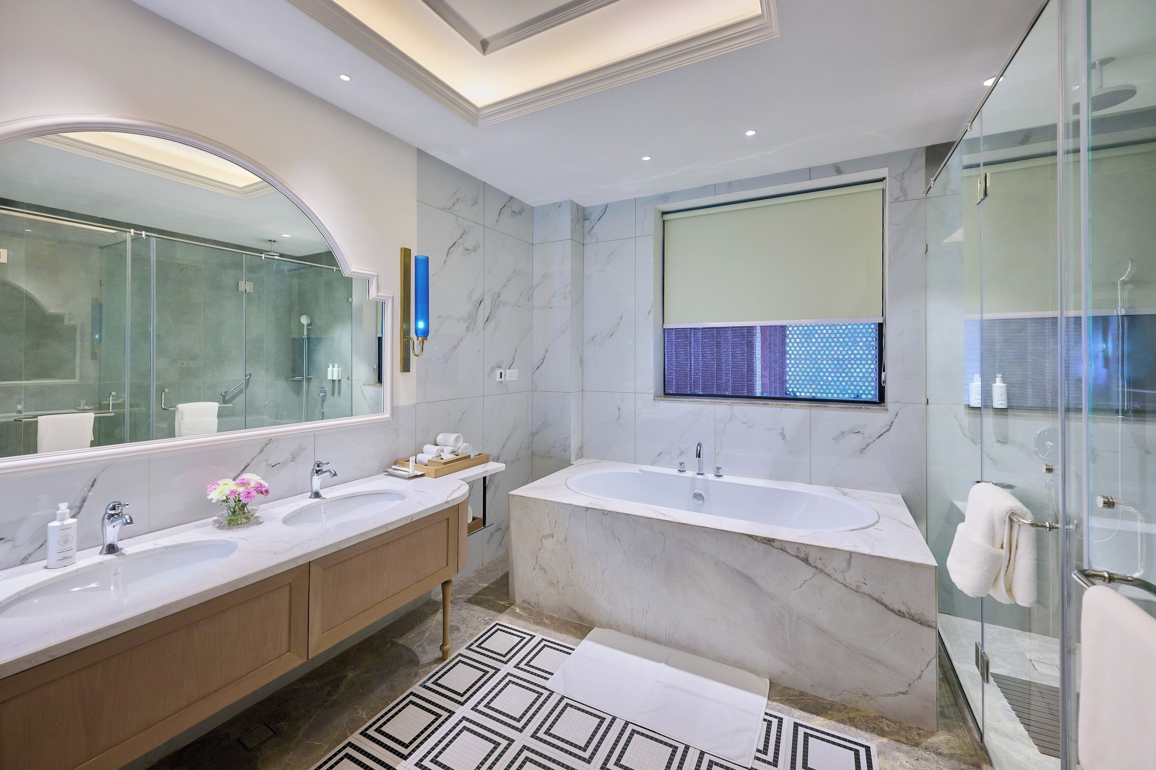 A modern bathroom with two sinks, a large bathtub, and a glass shower enclosure.