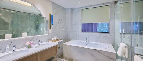 A modern bathroom with two sinks, a large bathtub, and a glass shower enclosure.