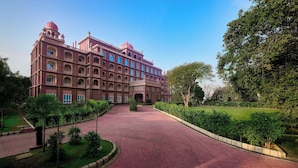 A large, multi-story building with a central courtyard, surrounded by greenery and a paved walkway. - Sarovar Premiere Amritsar (Amritsar)