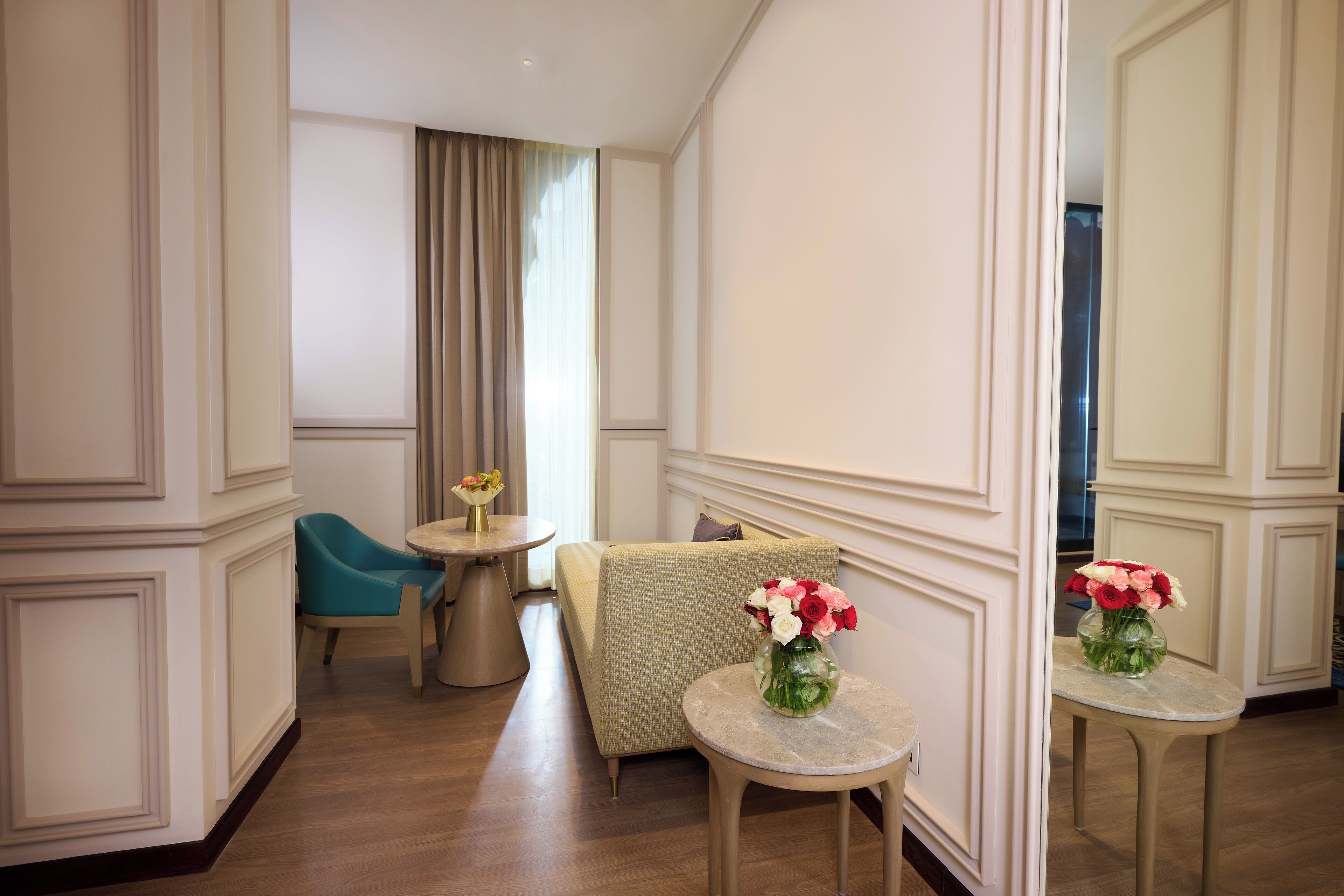 A hotel room with a sofa, a small round table, and a mirror.